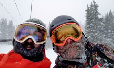 Skiers wearing ski masks and goggles ride the chair lift