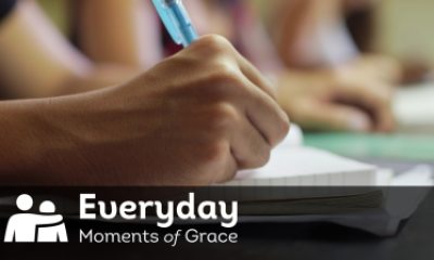 Text of "Everyday Moments of Grace" overlaid on close-up of hand and pen