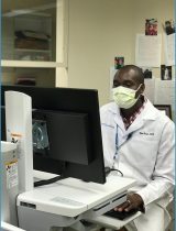 Titus Kosgei, DNP, works at a computer in the clinic