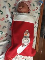A sleeping newborn baby wrapped in a holiday stocking 