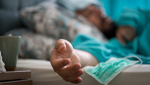 A patient lies on a bed with an outstretched hand in the foreground