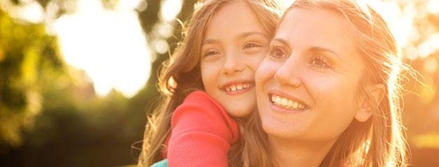 A mother and daughter smiling with the sunshine behind them