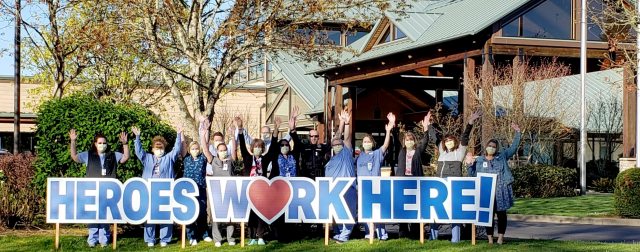 Heroes work here text, overlaid on photo of group of caregivers