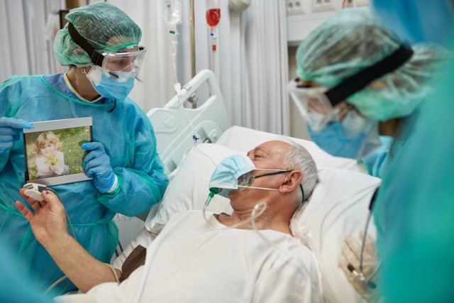 Surgeons show a photo to a patient in a hospital bed
