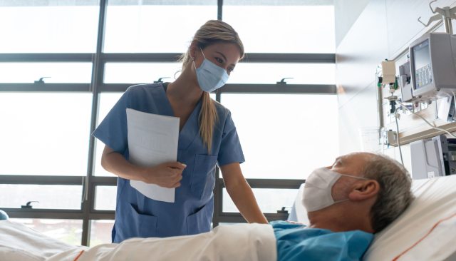 A nurse provides care to patient in a hospital bed