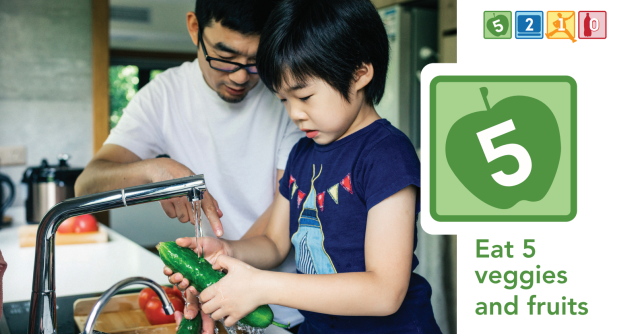 A Father and son wash a cucumber and other vegetables to prepare for eating