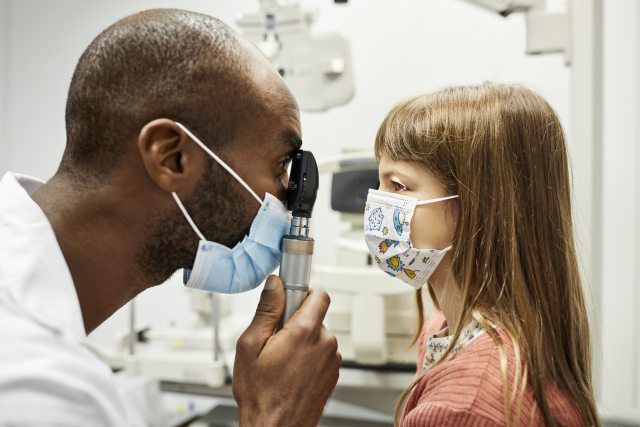 Eye doctor examines eyes of young child