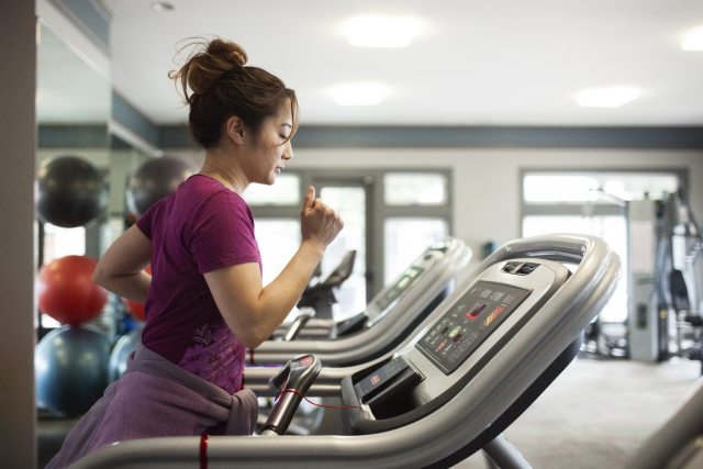 Woman working out on a treadmill at a gym.