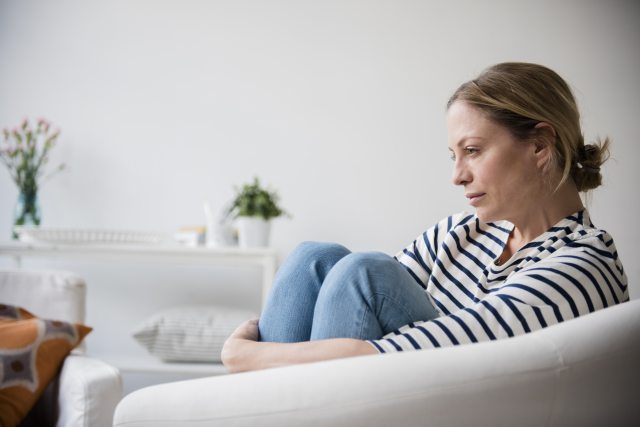 Woman on a couch looks off into space