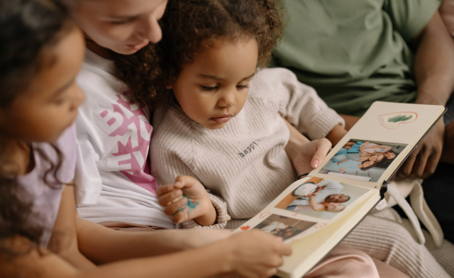 A young family flips through a photo album together.
