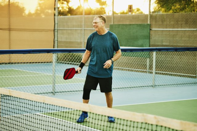 Older man playing pickleball. 
