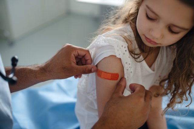 Little girl getting bandaid put on after vaccine.
