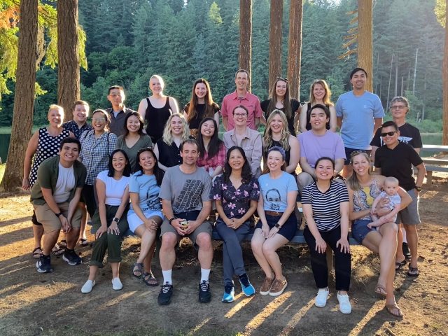 A group of residents pose for a large group photo in a forest or park like setting