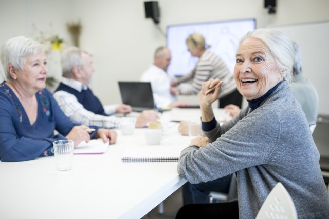 Seniors sitting around a table smiling and talking