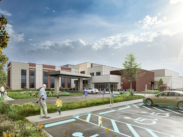 Image of a building with windows, and trees and parking in front