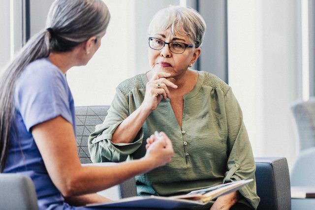 A senior adult woman listens carefully as a female doctor explains a concept to her.