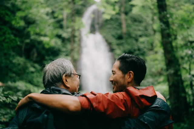 Father and son on bench in conversation in front of a waterfall