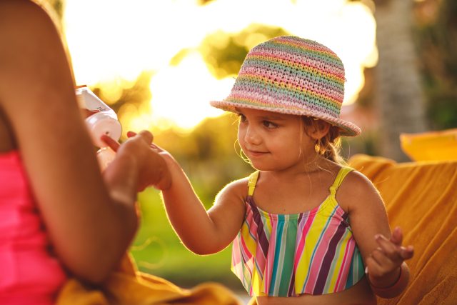 Woman applying sunscreen to young child.