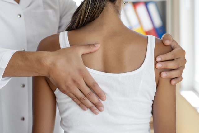 Close up of hand of provider checking the back of a young woman