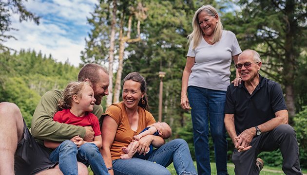 four adults with a young child and baby enjoying sunny day outside