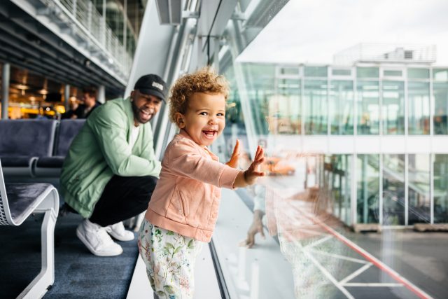 Dad looking at young daughter in airport.