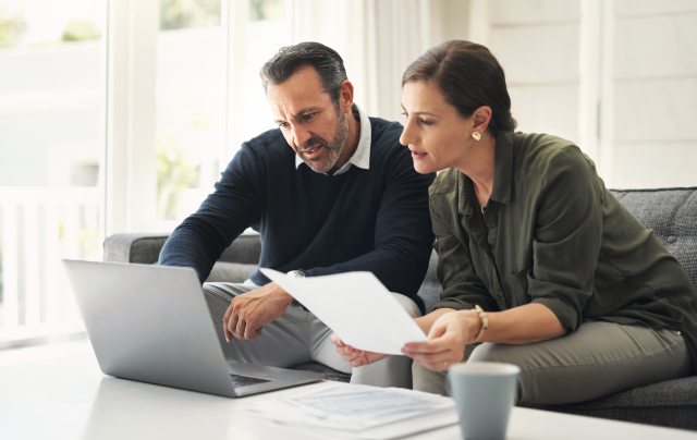 Male and female looking at computer and important documents.