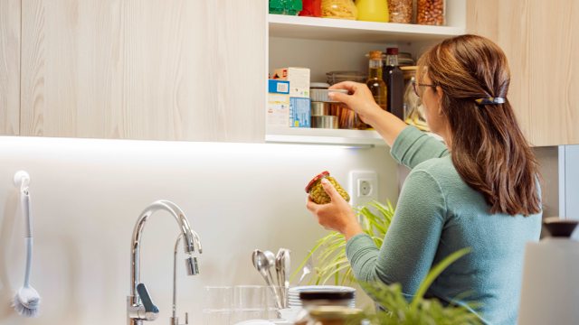 Woman puts jars of food into the cupboard
