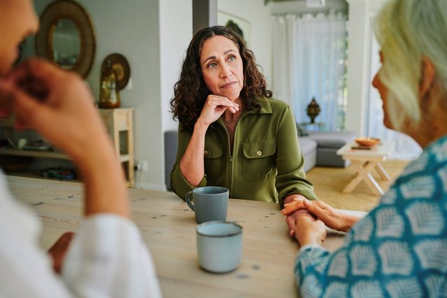 Three women seated at a table for a serious conversation