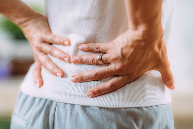Close-up of hands of someone holding lower back