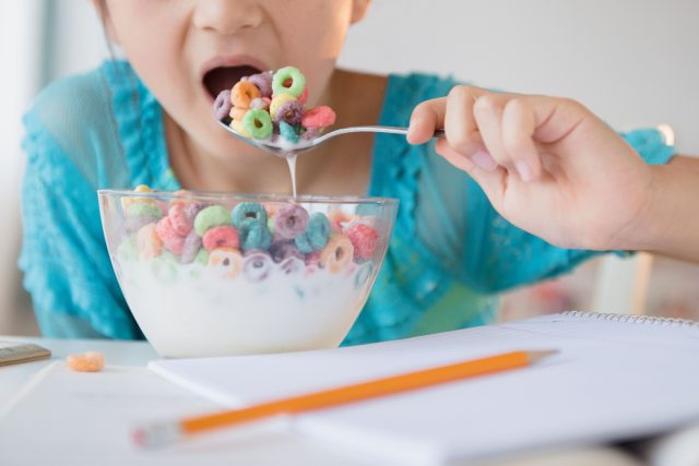Close-up of child's hand putting a spoonful of kids' cereal in mouth