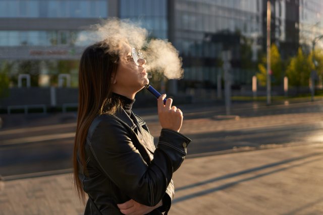 Woman uses vaping pen outside an office building
