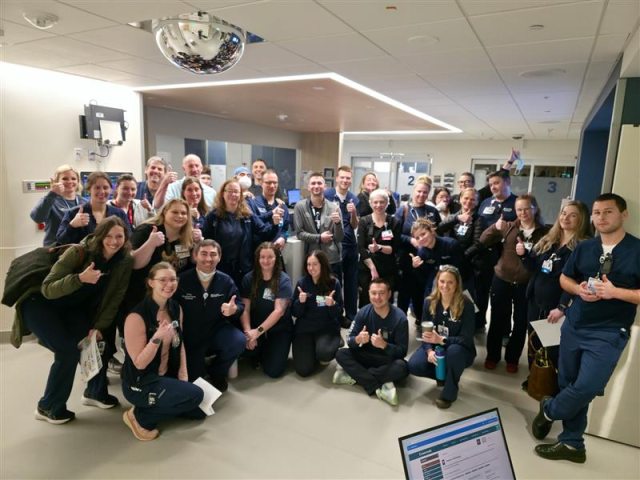 A large group of caregivers smiling at the camera in the new emergency department