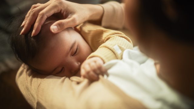 Baby nurses at breast as mom strokes head of baby
