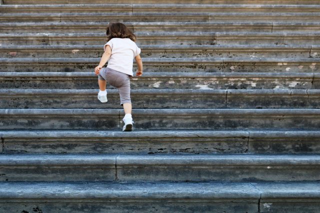 Small child climbs steps outside