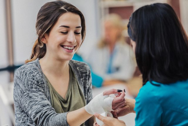 A caregiver dresses a wound of a smiling patient