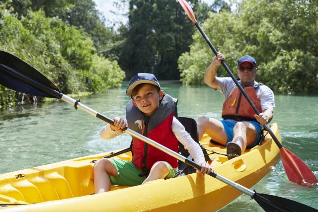 Child and man paddle in a yellow canoe