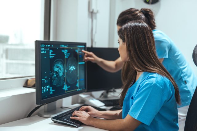 Two nurses view a scan on a computer monitor