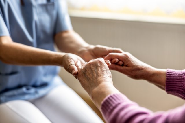 A caregiver and patient grasp hands