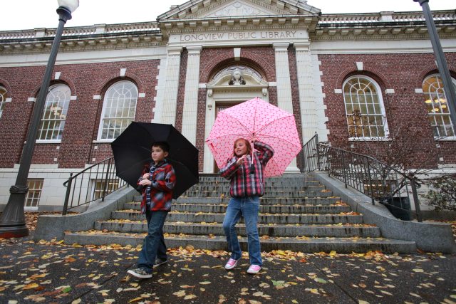 Two children with umbrellas walking down the steps of the public library