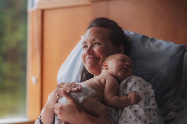 A happy mother holds her newborn child