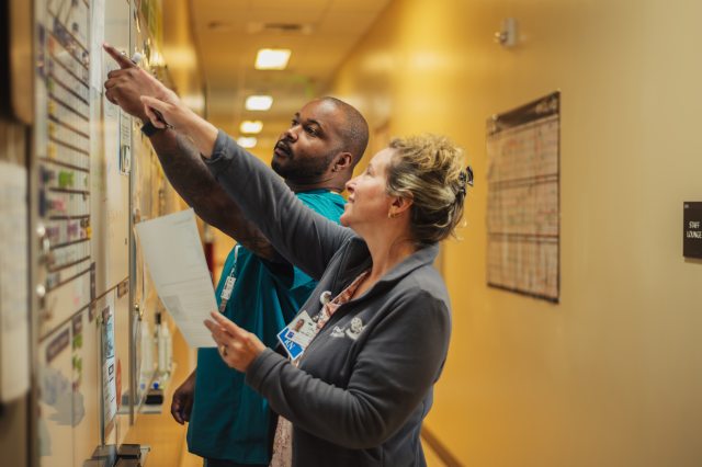 Two PeaceHealth caregivers discuss a patient triage board