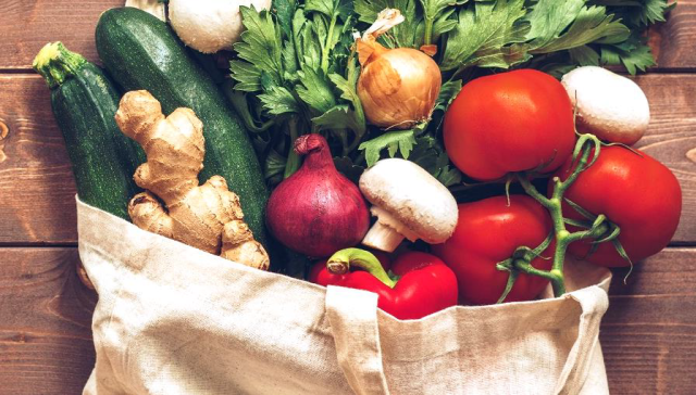 Vegetables in a bag, semi scattered across a wooden table