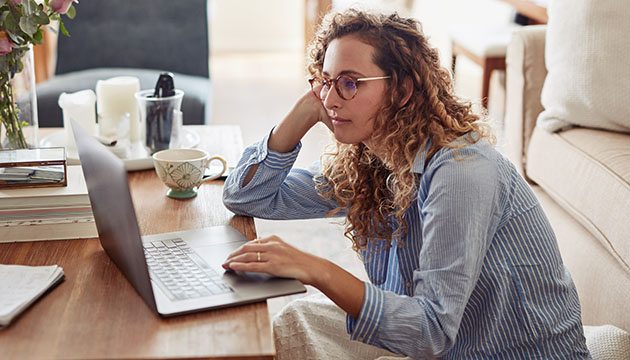Young professional woman stares at laptop with defeated look.
