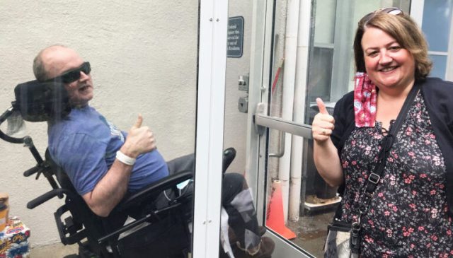 Sister visits brother in long-term-care facility behind glass