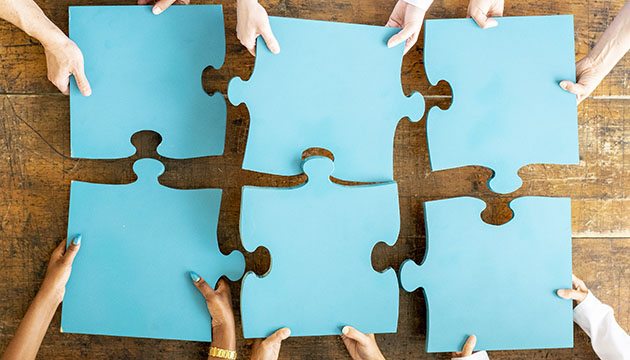 Close-up of hands configuring giant puzzle pieces properly