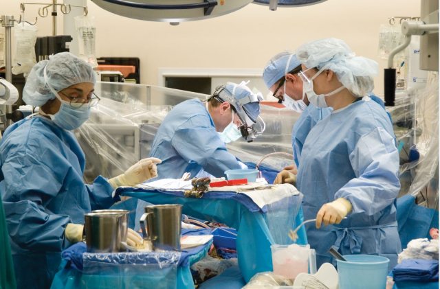 A team of surgeons and supporting providers performing surgery
