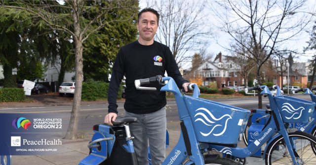 Dr. Hans Notenboom standing next to a bicycke with the PeaceHealth logo