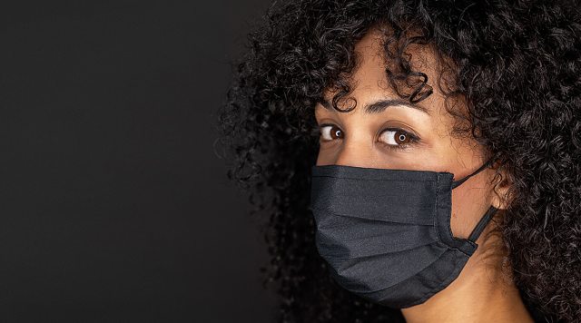A masked woman looks into the camera