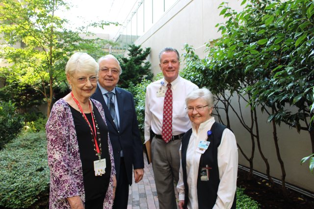 A group of PeaceHealth volunteers stands near a garden