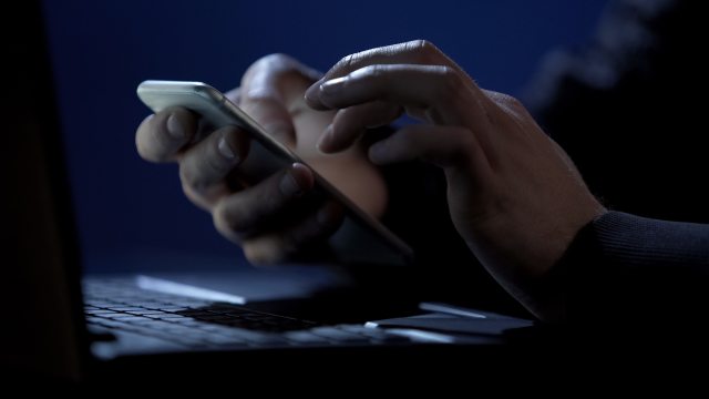 close up of hands holding cell phone in a dark room